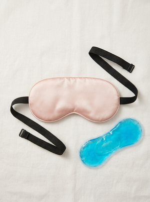 Silensea cooling sleep mask in Blush Pink laid flat beside its reusable gel pack