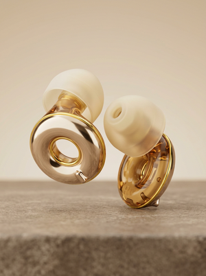 Pair of Silensea earplugs in Brushed Gold on a concrete ledge