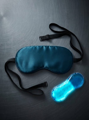 Silensea cooling sleep mask in Midnight Navy laid flat beside its reusable gel pack